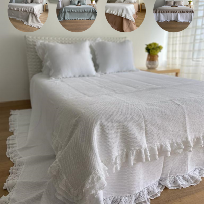 Colcha branca com franjas rendadas numa cama em quarto luminoso