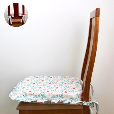 Capa de assento floral amarrada numa cadeira de madeira