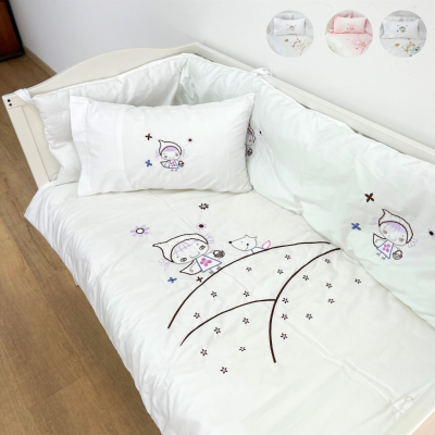 Roupa de cama infantil branca com bordados coloridos em cama de madeira clara