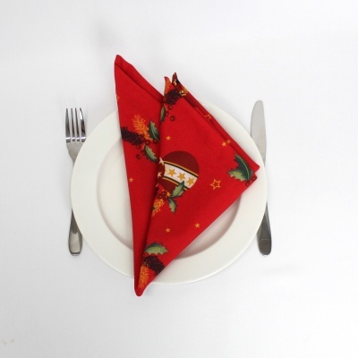 Guardanapo de tecido vermelho com padrão de Natal em prato branco com talheres