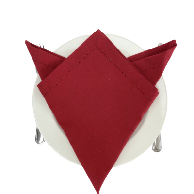 Guardanapo vermelho dobrado sobre prato branco com talheres