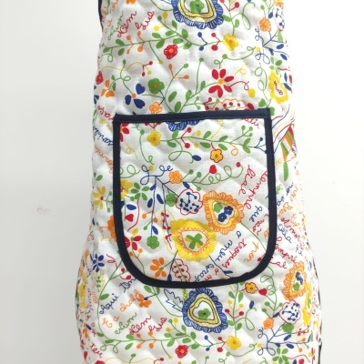 Avental floral colorido com bolso frontal e texto decorativo