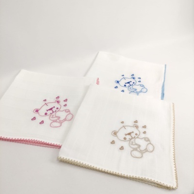 Fraldas de pano brancas com bordas coloridas e bordado de ursinho com corações.