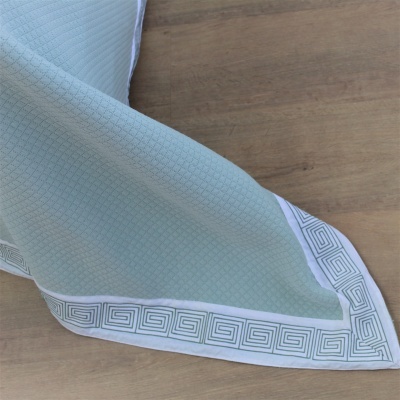 Toalha de mesa azul clara com borda branca e padrão geométrico