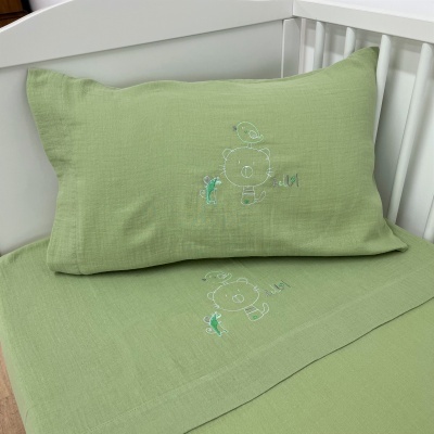 Jogo de cama verde claro com bordados em berço branco
