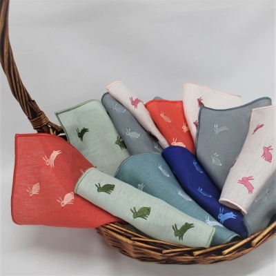 Lenços bordados com coelhos coloridos numa cesta de verga