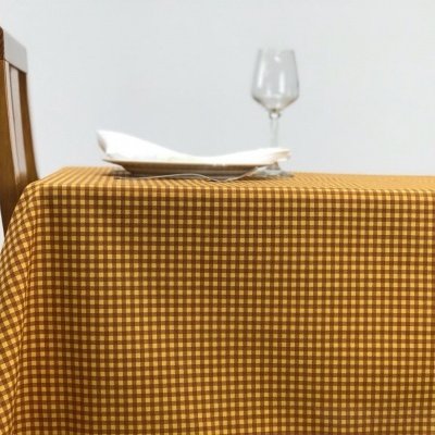 Toalha de mesa xadrez amarelo e castanho com prato, guardanapo e copo