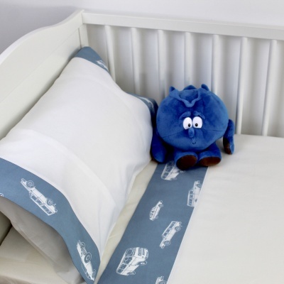 Cama de bebé com almofada branca e brinquedo de pelúcia azul.