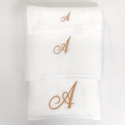 Três toalhas brancas com letra A dourada bordada