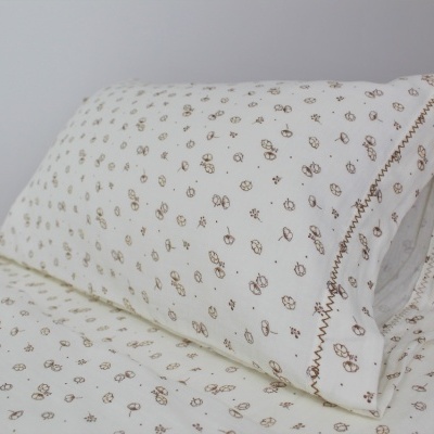 Conjunto de roupa de cama branco com padrão castanho e almofada em cama de madeira clara