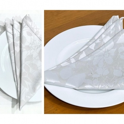 Guardanapos de tecido branco com padrão floral em pratos brancos