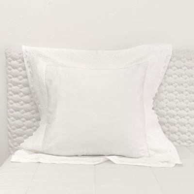 Almofada branca com fronhas texturizadas sobre cama branca