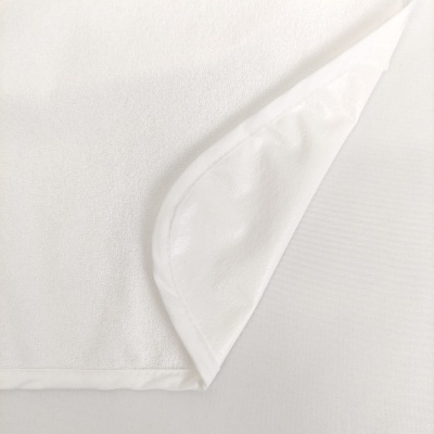 Toalha branca macia com dobra a mostrar verso liso e acabamento nas bordas