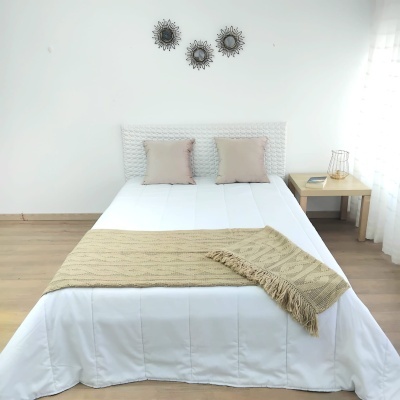 Cama de casal com roupa de cama branca e decoração minimalista no quarto