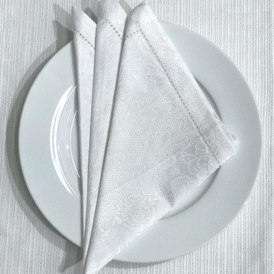 Guardanapos de tecido branco com padrão floral sobre prato branco