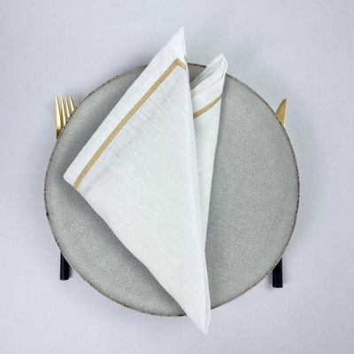 Prato cinza redondo com guardanapo branco e talheres dourados e pretos