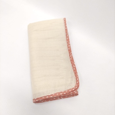 Guardanapo branco com borda estampada rosa e branca dobrado sobre fundo branco