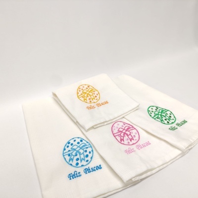 Toalhas brancas bordadas com tema de Páscoa em várias cores.