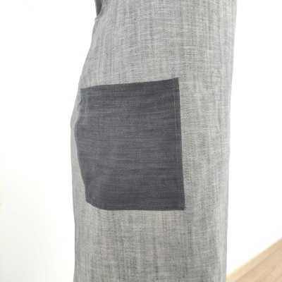 Peça de vestuário cinza claro com bolso cinza escuro e textura de tecido