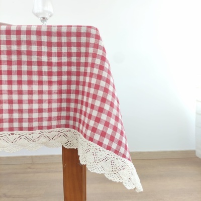 Toalha de mesa xadrez vermelho e branco com renda branca numa mesa de madeira.