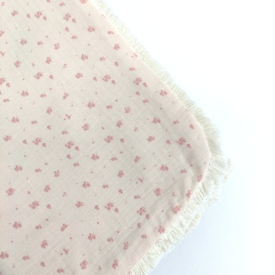 Toalha ou pano rosa claro com pequenos padrões e bordas franjadas