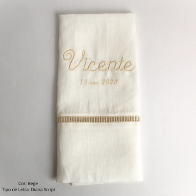 Guardanapo bege com bordado Vicente 18 nov 2023 e detalhe trançado