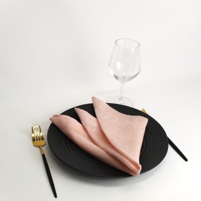 Conjunto de jantar com prato preto, guardanapo rosa e talheres preto e dourado