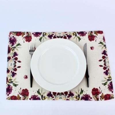 Individual de mesa com padrão floral, prato branco, garfo e faca com cabos pretos