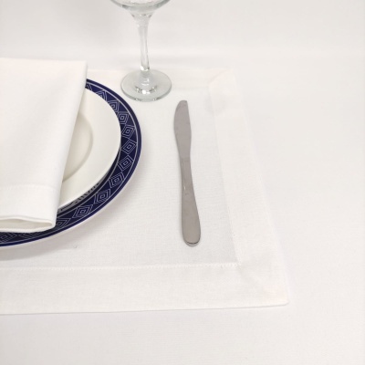 Conjunto de mesa com prato branco e azul, guardanapo branco, faca de metal e copo de vidro