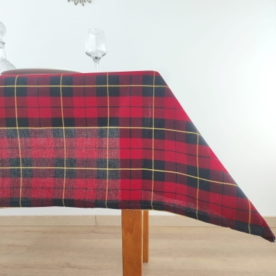 Toalha de mesa xadrez vermelho e preto sobre mesa de madeira com duas taças de vidro ao fundo