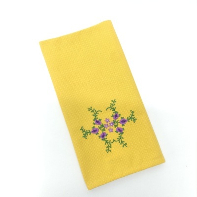 Pano de cozinha amarelo com bordado de flores roxas e verdes