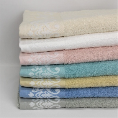 Toalhas coloridas empilhadas com padrão decorativo branco numa das bordas