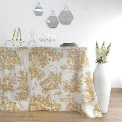 Toalha de mesa branca com padrão floral amarelo com copos, garrafa, pratos, espelhos e vaso com flores