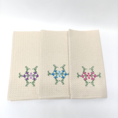 Três toalhas de cozinha bege claro com bordados florais coloridos