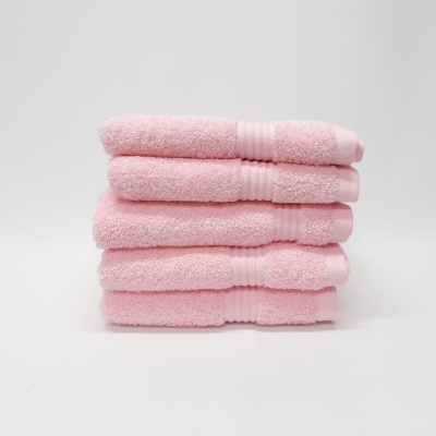 Quatro toalhas de banho cor-de-rosa empilhadas sobre fundo branco