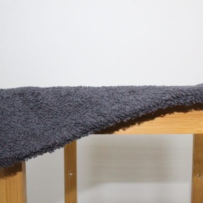 Toalha cinzenta escura felpuda pendurada numa estrutura de madeira