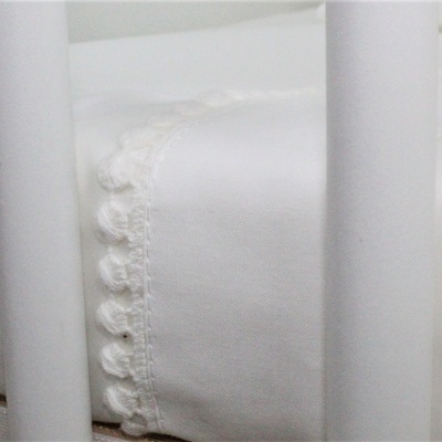 Colchão branco com bordado em tecido branco e estrutura metálica branca