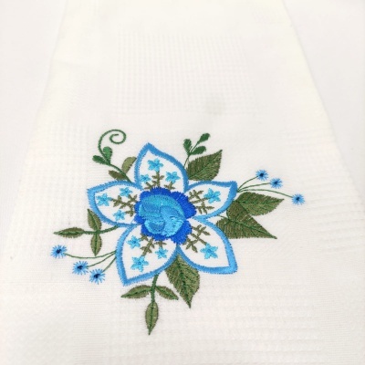 Toalha branca com bordado floral azul e folhas verdes