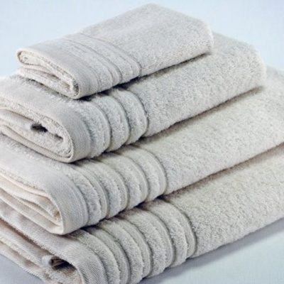 Conjunto de toalhas bege claro empilhadas com faixas texturizadas.