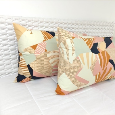 Duas almofadas decorativas com estampado geométrico colorido sobre cama branca