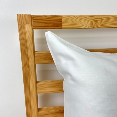 Cabeceira de cama em madeira clara com almofada branca