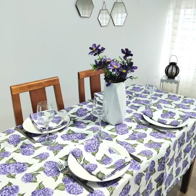 Toalha de mesa e guardanapos com padrão floral lilás em mesa de madeira com pratos e copos