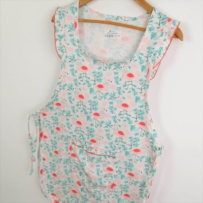 Macacão infantil branco com padrão floral verde e rosa pendurado em cabide