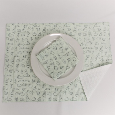 Conjunto de toalhetes para mesa verdes com padrão de embutidos sobre prato branco