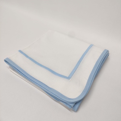 Toalha branca com bordas azuis claras dobrada sobre superfície branca