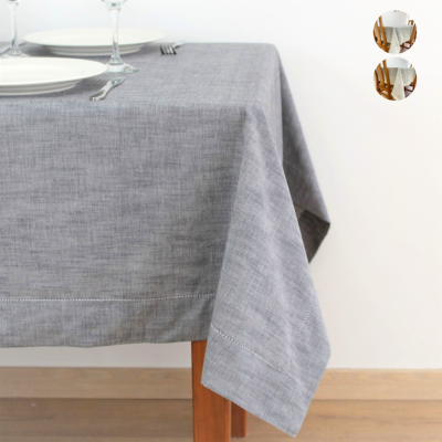 Toalha de mesa cinzenta de linho numa mesa de madeira com pratos e copos