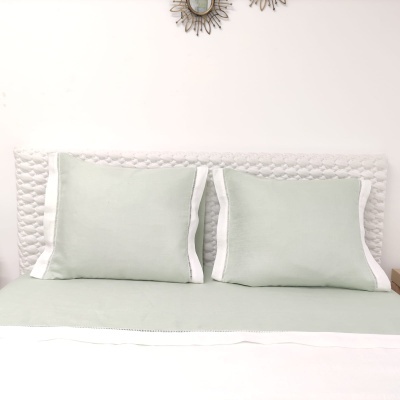 Conjunto de cama com almofadas verdes e cabeceira branca acolchoada