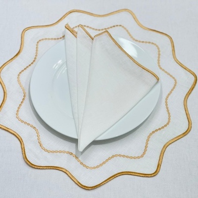 Prato branco com pega de prato transparente com borda dourada e guardanapo branco com borda dourada