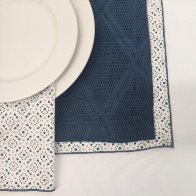Toalha de mesa azul escuro e branca com padrão floral e prato branco