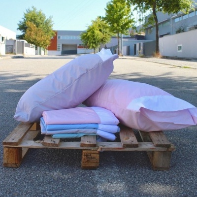 Conjunto de roupa de cama rosa e azul sobre pallet de madeira em rua urbana